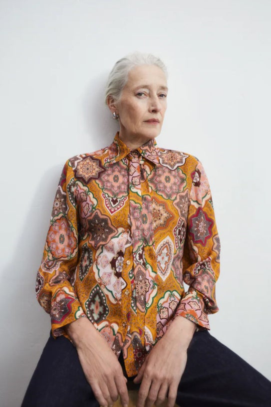 Diseño multicolor en tonos rosados y marrones sobre fondo naranja para esta camisa satinada fluida de Zara que viene con cuello de solapa con lazo y mangas largas. Podemos encontrarla entre las tallas XS y XL por 25,95 euros. 