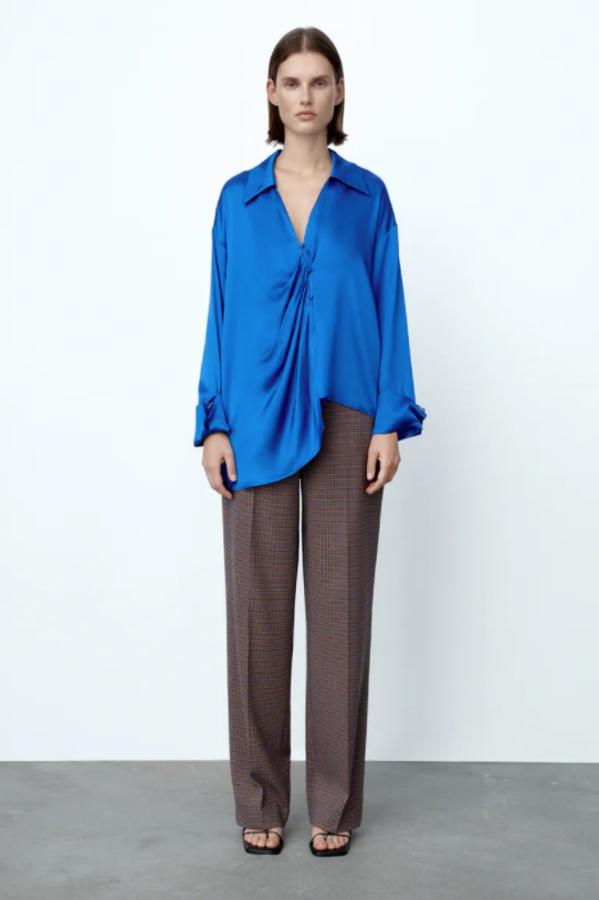 Diseño oversize para esta camisa de Zara en azulón que viene con cuello solapa, escote de pico y mangas largas acabadas en vuelta. Tiene detalle de frunces delanteros y bajo asimétrico, cuesta 29,95 euros y está disponible entre las tallas XS y XL. 