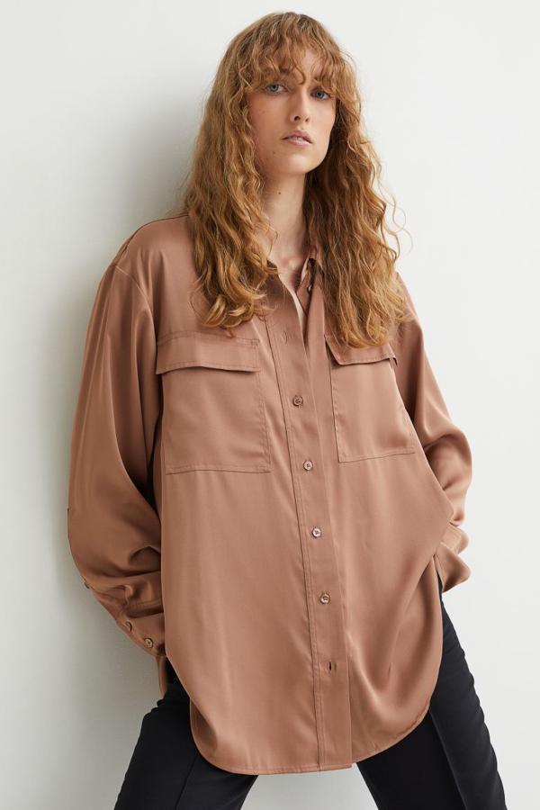 Disponible en beige grisáceo, marrón claro y blanco, esta camisa en satén fluido de H&M viene con cuello camisero, cierre de botones frontal y bolsillos de plastrón con solapa en la pechera. Tiene el bajo redondeado, cuesta 24,99 euros y está disponible entre las tallas XS y XXL. 
