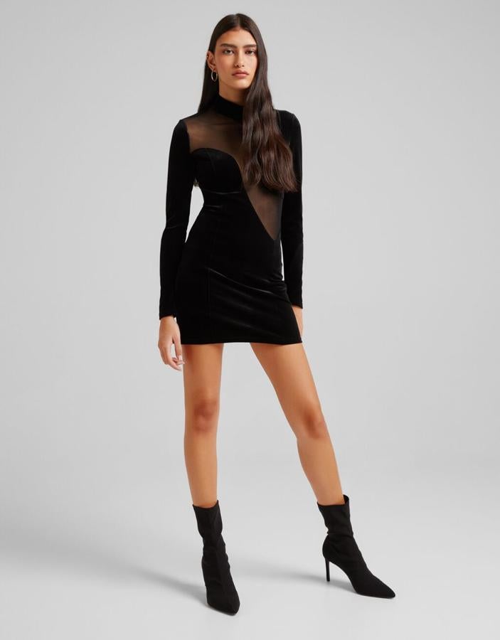 Este vestido mini de terciopelo negro de Bershka con aplicación de tul en la parte superior viene con cuello alto y mangas largas y podemos encontrarlo entre las tallas XS y XL por 25,99 euros. 