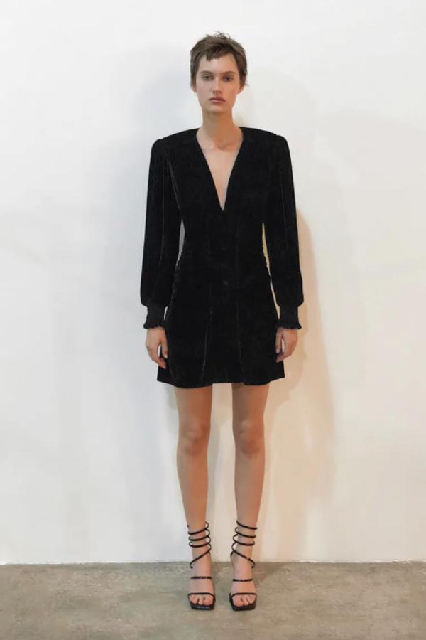 Escote de pico y mangas largas acabadas en elástico tipo nido de abeja para este vestido mini de terciopelo de Zara con detalle de pliegues laterales y cierre frontal de botones en el mismo tejido que podemos encontrar entre las tallas XS y XL por 29,95 euros.