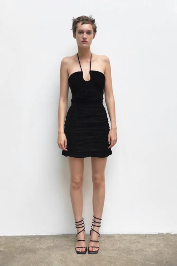 En la colección edición limitada de Zara hemos encontrado este vestido mini de terciopelo en color negro con escote recto con abertura y lazadas en el mismo tejido. Tiene pliegues laterales y elástico tipo nido de abeja, cuesta 49,95 euros y está disponible entre las tallas XS y XL.