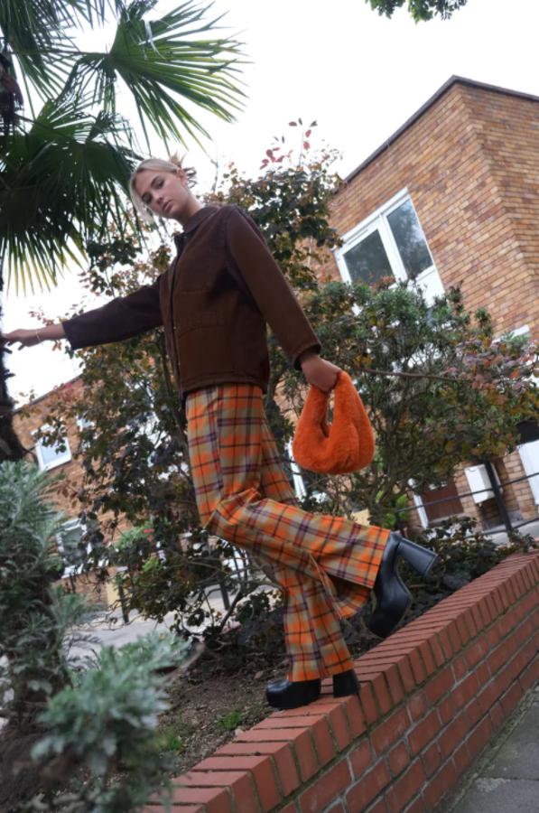 De tiro alto y con bolsillos laterales, este pantalón flare con estampado de cuadros en tonos toffe y naranja con púrpura es de Zara, viene con bajos acabados con abertura y cuesta 29,95 euros. Está disponible entre las tallas XS y XL. 