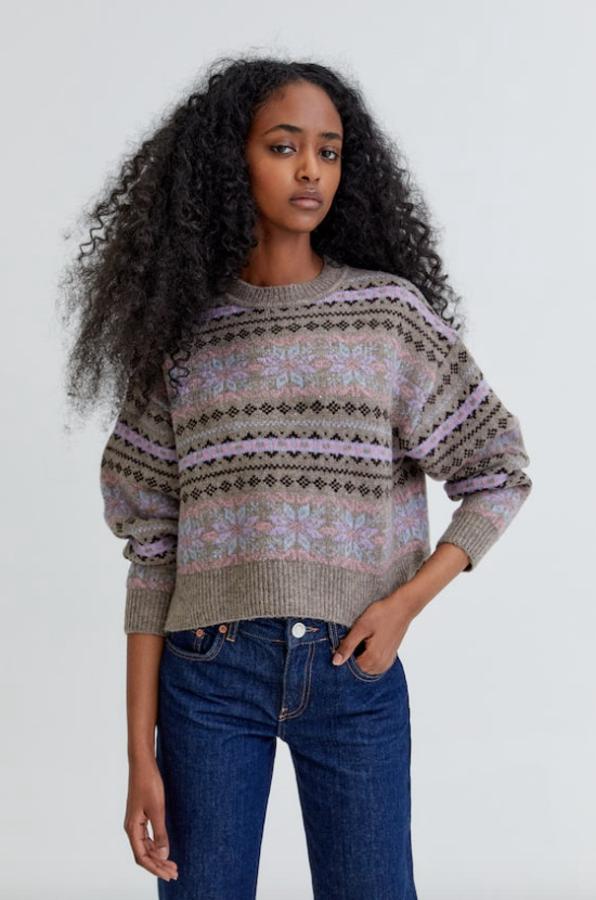 En color gris, con estampado en lila, azul y negro, este jersey en punto jacquard de Pull&Bear con mangas largas y cuello redondo está disponible entre las tallas XS y L y cuesta 29,99 euros.