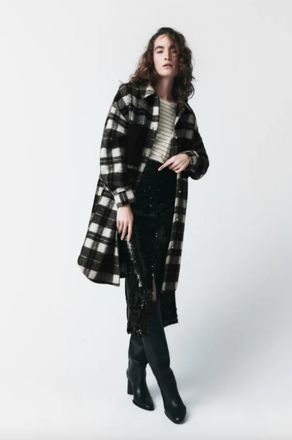 Con cuello de solapa y mangas largas, esta sobrecamisa larga de Zara con estampado de cuadros en blanco y negro viene con bolsillos delanteros combinados en tejido denim, bajo con aberturas laterales y cierre frontal de botones joya. Tiene un precio de 59,95 euros. 