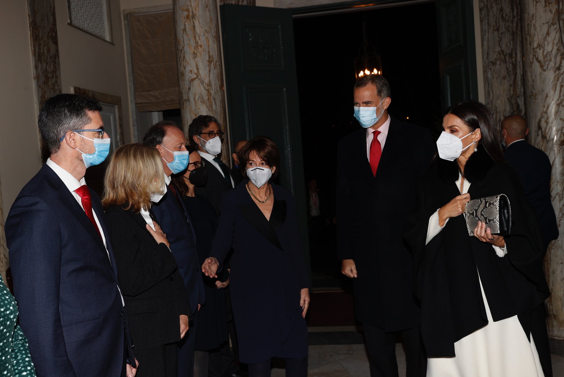 A su llegada a la Embajada de España en Estocolmo, doña Letizia lucía su capa negra de Hugo Boss, un abrigo que quedaba perfecto con su vestido blanco de marca desconocida.