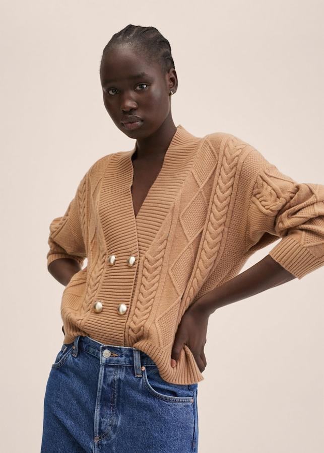 Tejido de punto trenzado para este cárdigan disponible en negro y en marrón medio que viene con escote de pico, costura del hombro caída, terminaciones de canalé y cierre frontal de botones metalizados y cuesta 29,99 euros. Podemos encontrarlo entre las tallas XXS y XXL. 