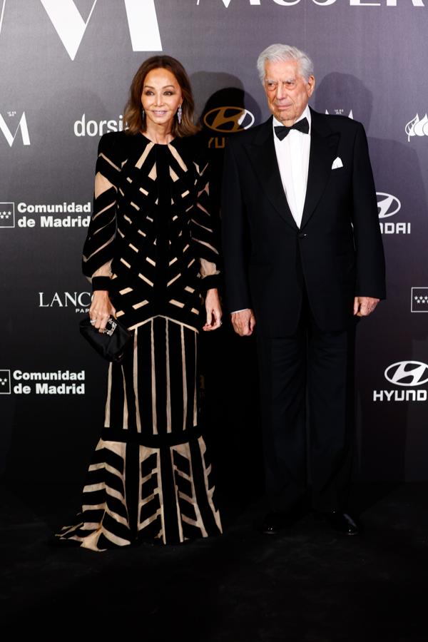 Una elegantísima Isabel Preysler posó junto a Mario Vargas Llosa con un vestido largo combinado en nude y negro de Teresa Helbig que conseguía un favorecedor efecto visual con transparencias. Lo combinó con joyas de Rabat y bolso de Bvlgari.