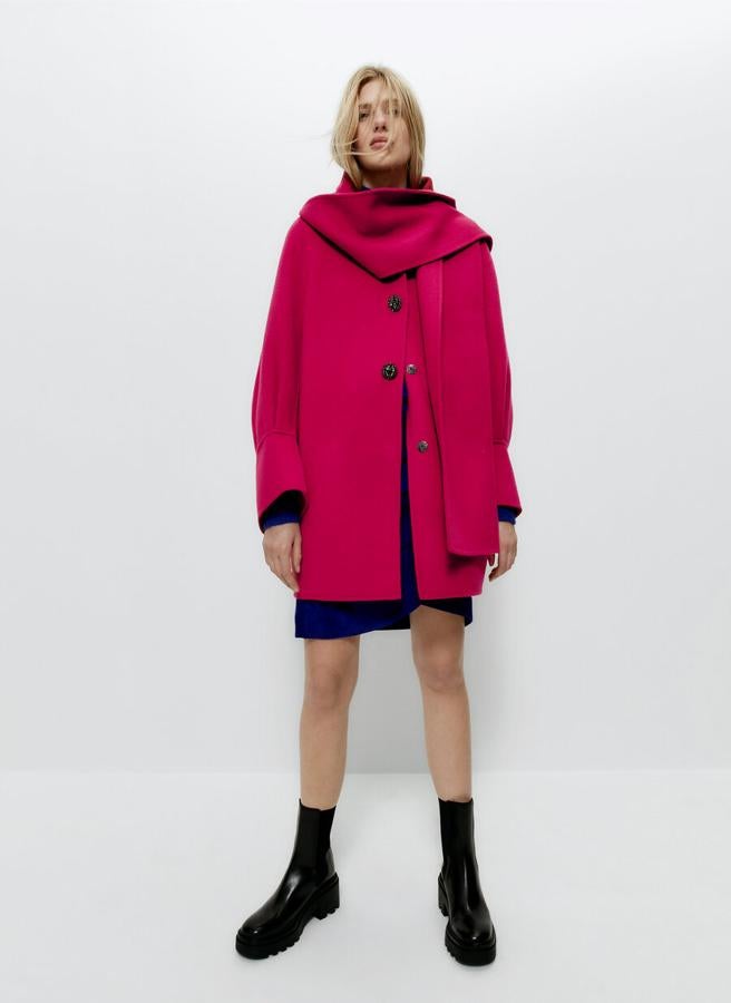 Diseño corto para este abrigo rosa de Uterqüe confeccionado en tejido de lana con técnica de puntada manual que viene con pieza desmontable a tono en el cuello y manga abullonada con pliegues. Tiene cierre frontal de botón joya y snap metálico y un precio de 229 euros. 