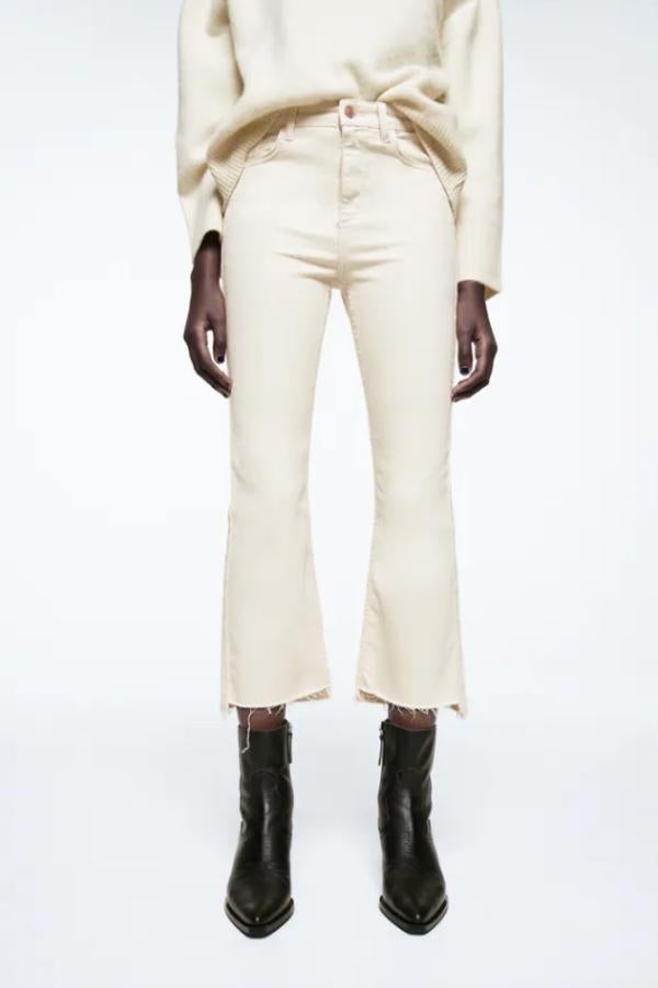 Bajo acabado en evasé con acabado asimétrico desflecado para estos vaqueros en color crudo de Zara que son de tiro alto, tienen cinco bolsillos y cuestan 22,95 euros. 