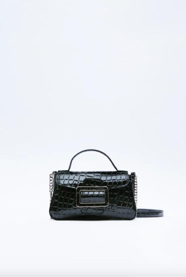 En formato bandolera mini, con estampado animal en efecto charol y detalle de hebilla a tono, este bolso de Zara con asa de mano y asa de cadena en función bandolera con cierre de imán podemos comprarlo por 19,95 euros. 