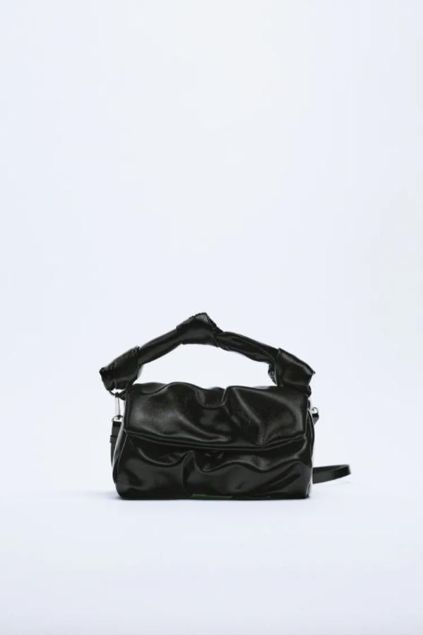 Con cuerpo soft y asa de mano con detalle de nudos, este bolso negro de Zara viene también con asa larga extraíble y tiene cierre de cremallera y solapa con imán. Cuesta 19,95 euros.
