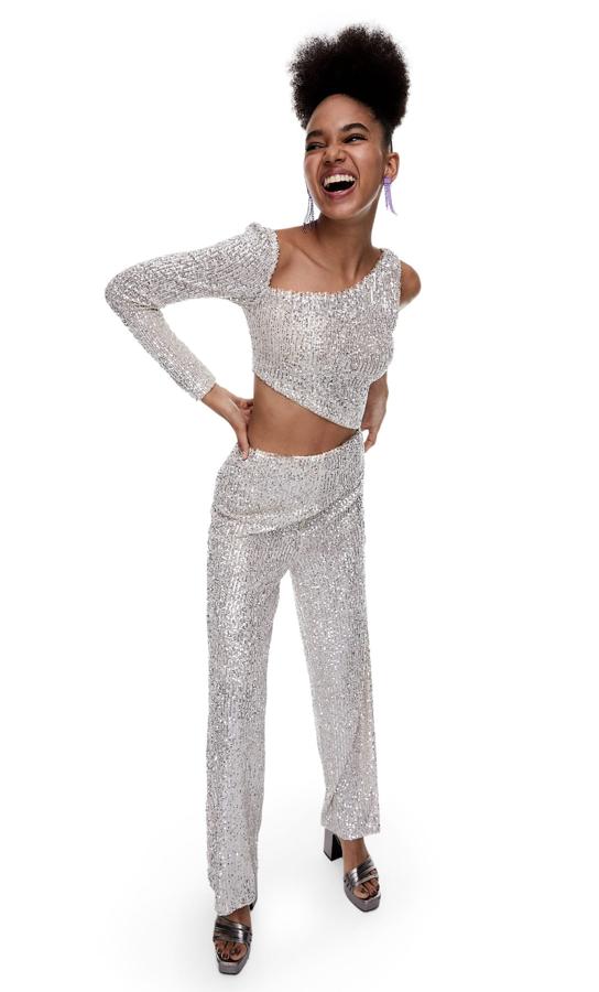 Con abertura en la cintura, escote asimétrico y una manga larga, este mono de lentejuelas en plata con perneras anchas es de Stradivarius y cuesta 39,99 euros. 