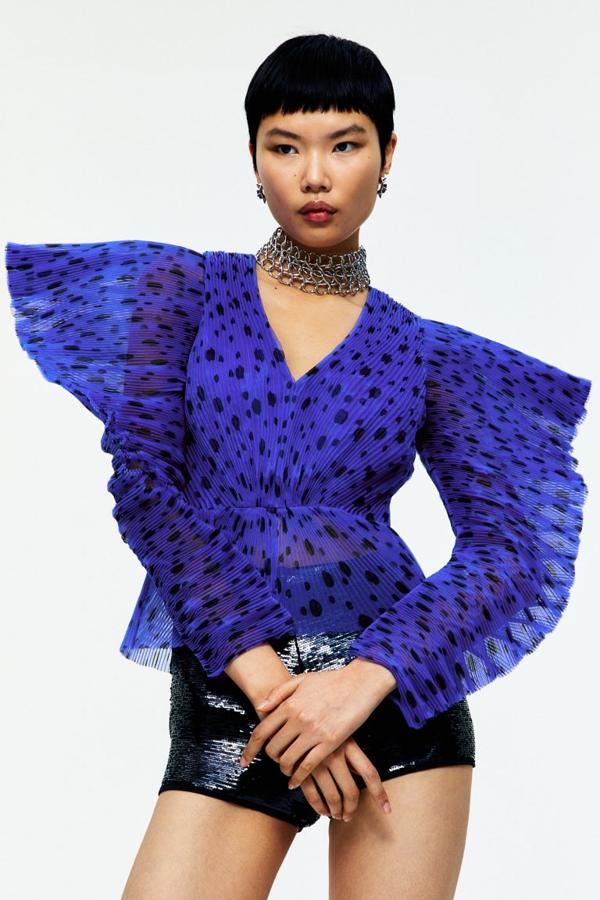 Blusa en organza plisada de con estampado digital. Modelo con escote de pico, hombros definidos con mangas asimétricas sobredimensionadas y corte a la cintura con peplo ligeramente evasé (69,99 euros).