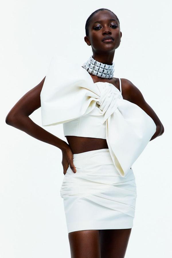 Top cropped en tafetán de con efecto frufrú. Modelo adornado con un lazo sobredimensionado relleno de tul para un toque extra de volumen y textura. Tirantes ajustables, varillas y cremallera en un lateral (59,99 euros).