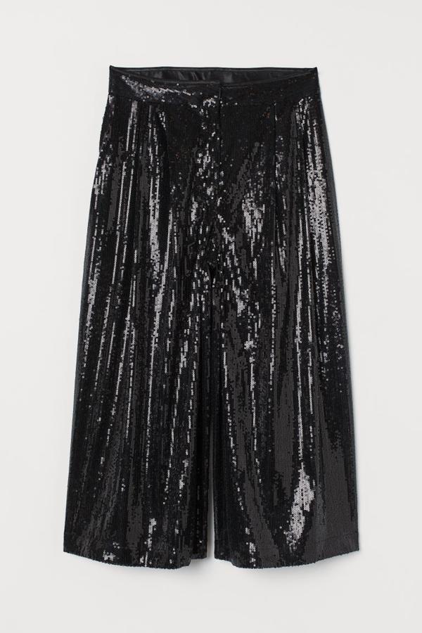 Con bajo hasta la rodilla y perneras amplias, este pantalón negro con lentejuelas de H&M es de talle alto con pinzas y solo se puede comprar en la web de la firma por 49,99 euros.