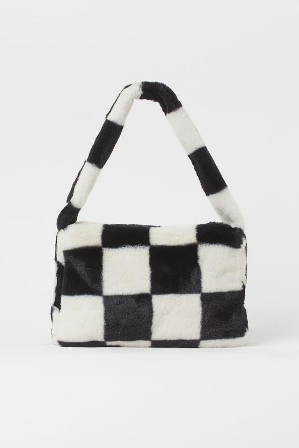 Esta bandolera en pelo sintético suave en blanco y negro es de H&M y viene con asa fija y cierre superior de cremallera. Cuesta 14,99 euros. 
