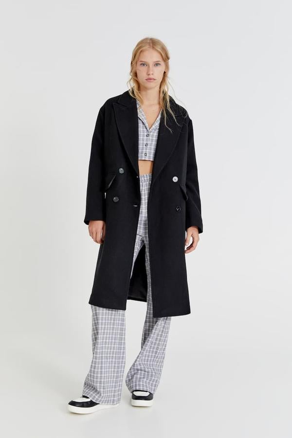 En Pull&Bear también han apostado por el diseño largo para este abrigo negro con cuello de solapa, cierre cruzado de botones a tono y bolsillos laterales de solapa. Con falsos botones en los puños, cuesta 49,99 euros. 