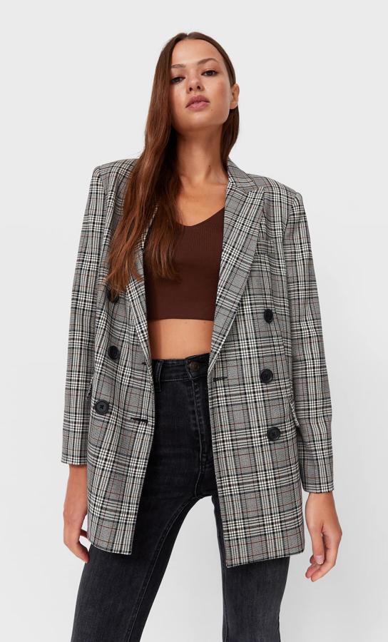 Estampado de cuadros en tonos negros, grises y rojos para esta americana de Stradivarius de cierre frontal cruzado con botones a contraste en negro. Con hombros marcados y bolsillos laterales con solapa, tiene un precio de 35,99 euros.