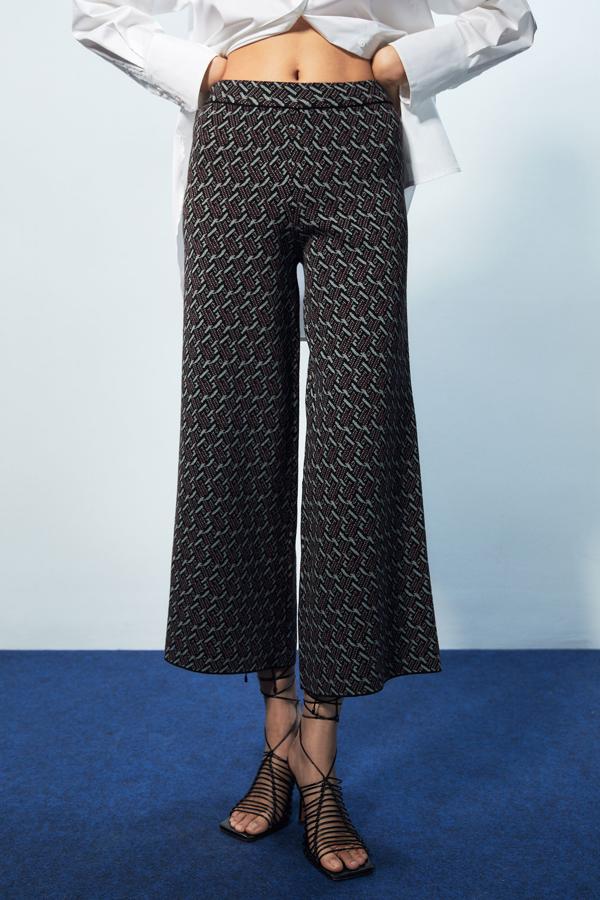 Este precioso pantalón en jacquard geométrico en tonos grises y granate viene con cintura elástica, perneras amplias y bajos ligeramente acampanados. Podemos comprarlos por 25,99 euros. 