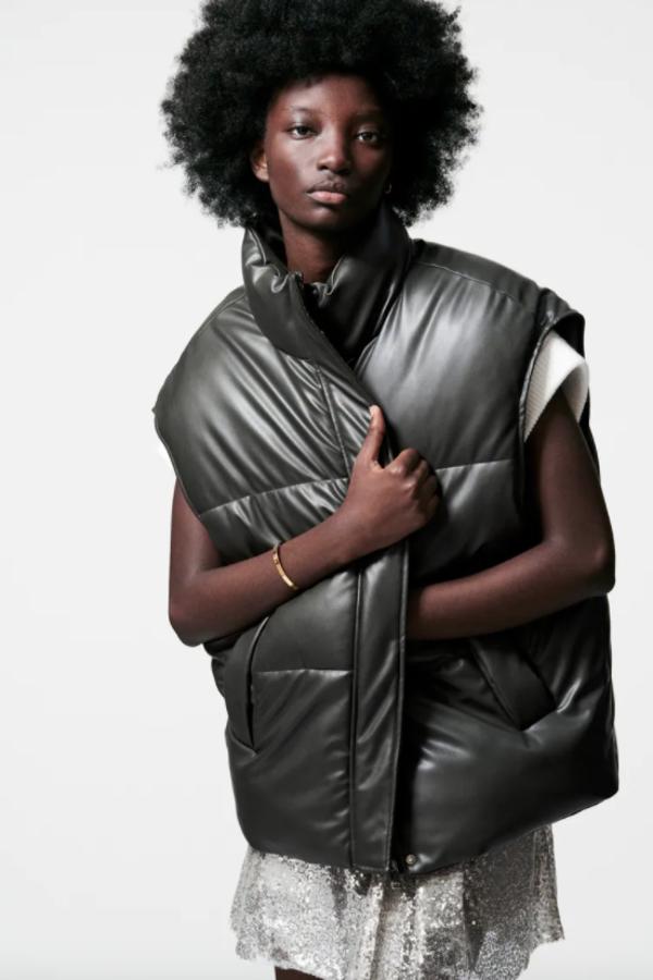 Con bolsillos delanteros de vivo y cuello subido con manga sisa, este chaleco oversize en verde botella tiene bajo ajustable con cordones elásticos y cierre frontal con cremallera y botones a presión ocultos. Cuesta 49,95 euros.