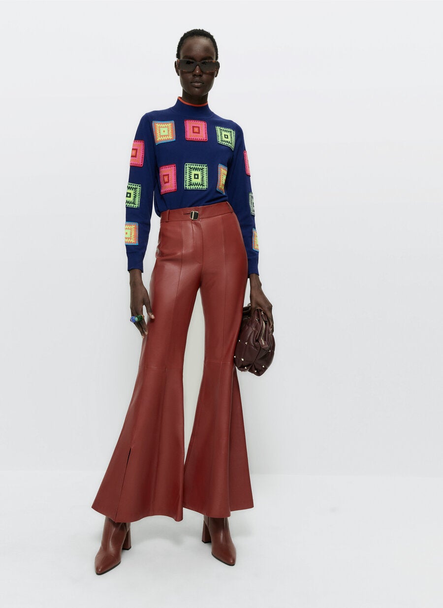 Este original jersey de Uterqüe con parches de macramé de diferentes colores sobre fondo azul oscuro viene con cuello perkins, mangas largas y acabados en rib. Cuesta 99 euros.