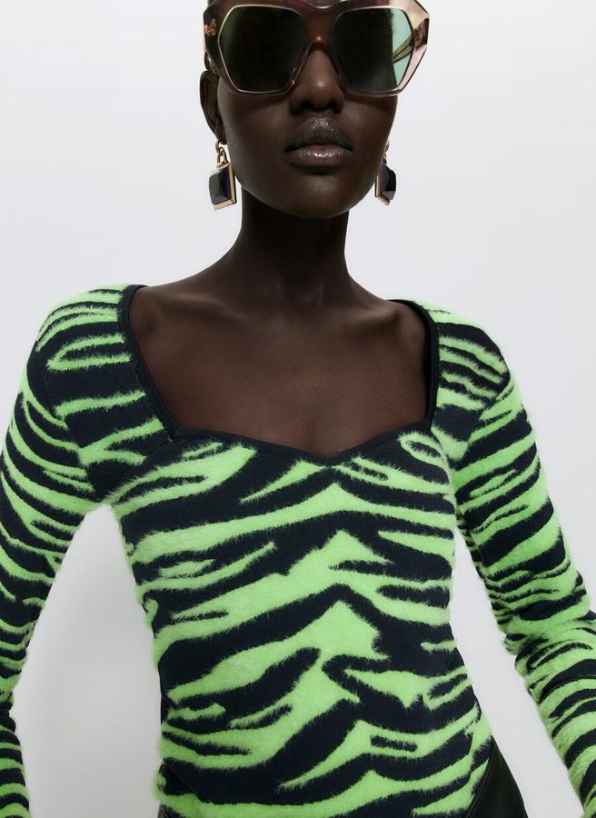 Con escote corazón y confeccionado en punto jacquard con estampado de cebra en negro y lima, este jersey de mangas largas de Uterqüe cuesta 89 euros. 