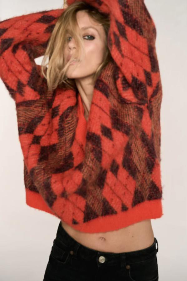 Diseño de rombos para este jersey confeccionado en tejido de mezcla de alpaca en tonos naranjas y marrones que tiene escote de pico y mangas largas y un precio de 49,95 euros. 