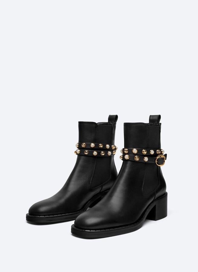 Estos botines negros vienen con cadena extraíble con perlas y elásticos en los laterales, además de un tirador trasero. Con caña de 11 centímetros y tacón de 5, tienen un precio de 139 euros y solo queda en los números 41 y 42. 
