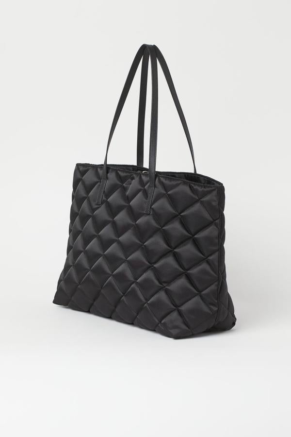 Diseño acolchado para este bolso negro de nylon en formato shopper que viene con doble asa de hombro y podemos comprar en H&M por 19,99 euros.