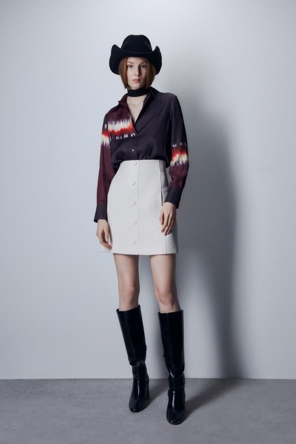 Diseño tie dye en naranja y blanco en el cuerpo y la manga para esta camisa satinada en color berenjena, con cuello camisero y cierre frontal de botones que tiene un precio de 19,99 euros. 