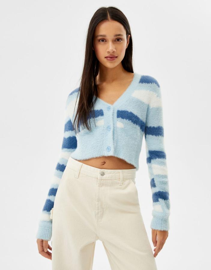 En dos tonos azul y blanco esta chaqueta de punto jacquard de diseño cropped, escote de pico y cierre frontal de botones a tono es de Bershka y podemos comprarla por 25,99 euros. 