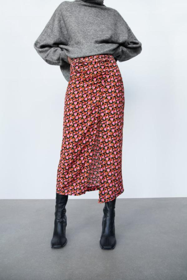 Estampado de flores en tonos rojos y rosas sobre fondo negro para esta falda midi de tiro alto con detalle de frunces en delantero y bajo con abertura que podemos encontrar en las rebajas de Zara por 7,99 euros, antes 22,95 euros, únicamente en las tallas XS y S.