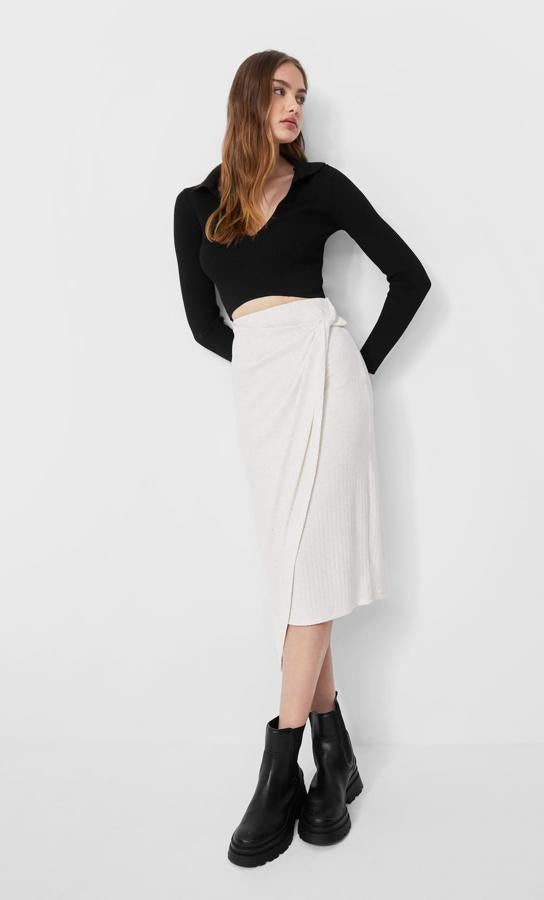 En color piedra, esta falda midi de punto de tiro alto con detall de nudo en la parte delantera y bajo asimétrico es de Stradivarius y de 17,99 euros ha pasado a costar 9,99 euros. Podemos encontrarla entre las tallas XS y XL. 