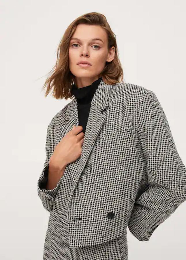 Estampado pata de gallo para esta blazer cropped de Mango de diseño cropped recto, con escote de pico con solapa, mangas con puños abotonados y cierre frontal de botón a contraste en negro. De 59,99 euros ha pasado a costar 22,99 euros y está disponible en las tallas L, XL y XXL. 
