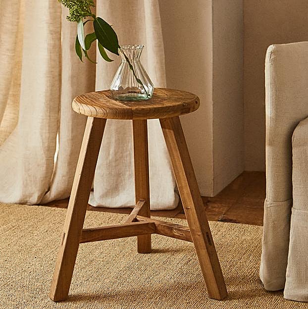 Imagen principal - El taburete de madera reciclada de Zara Home cuesta 59.99 euros y las dos mesas auxiliares de madera reciclada, 149 euros.