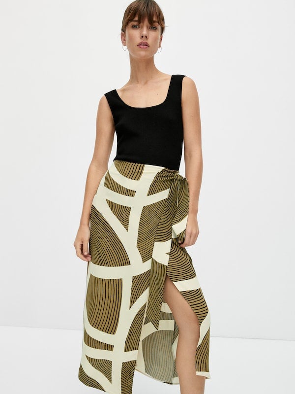 Cierre cruzado mediante lazada para esta falda midi de Massimo Dutti en tonos crudos y caqui que viene con bajo con abertura frontal y cuesta 59,95 euros. Está disponible entre las tallas 34 y 42. 