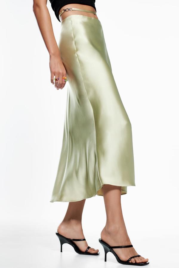 De tiro alto, con detalle de cinta en la cintura con aplicación metálica, esta falda de Zara en color cava, confeccionada en tejido satinado y con cierre lateral con cremallera oculta en costura tiene un precio de 22,95 euros y está disponible entre las tallas XS y XXL. 