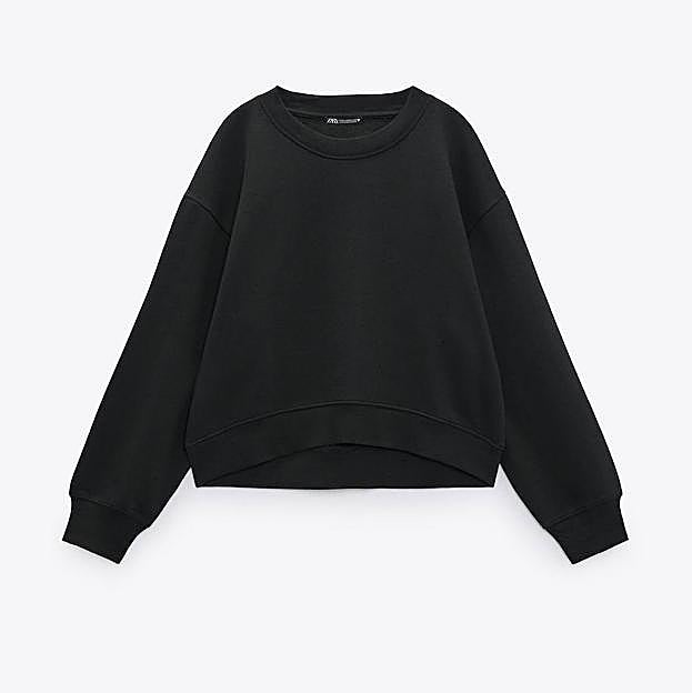 Imagen principal - Este look con sudadera negra de Zara y falda de lunares made in Spain se lleva con botas altas, camisa blanca y te quita 10 años de encima