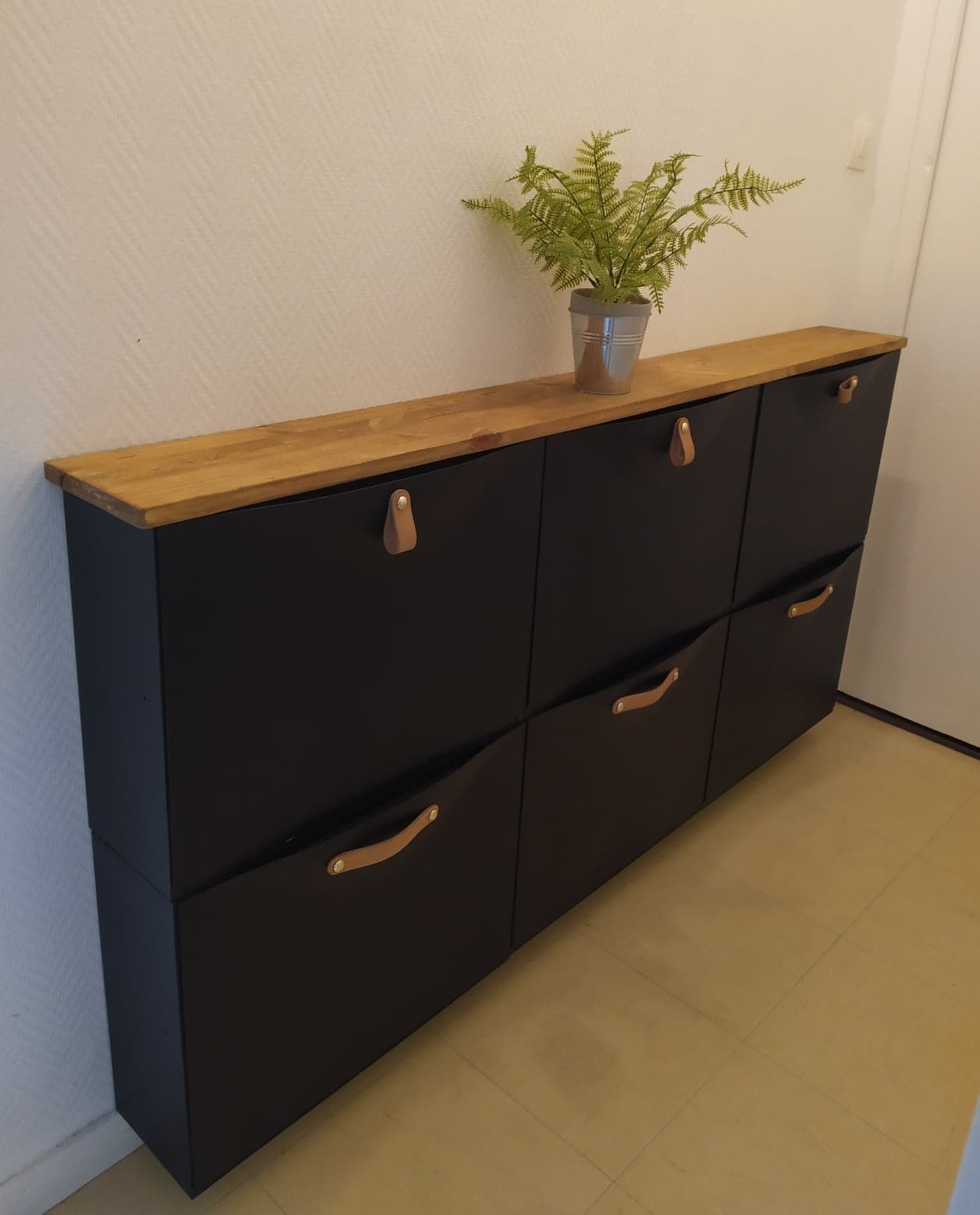 Tan sencillo como poner unos tiradores de cuero e incorporar una balda de madera en la parte superior, y conseguiremos que el zapatero Trones se convierta en un bonito mueble recibidor barato y versátil.