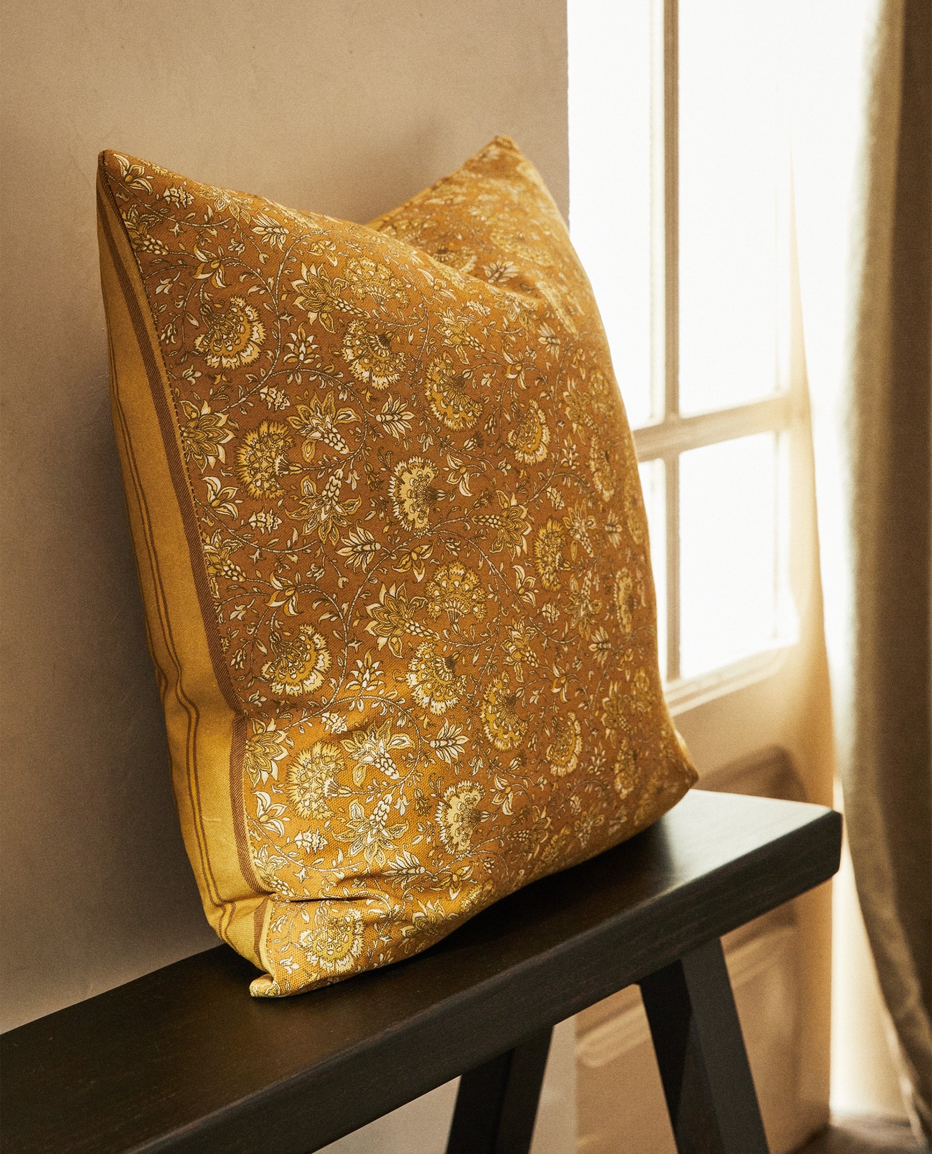 Zara Home apuesta fuerte por el color con textiles como estos elegantes cojines con original estampado floral en ocre (9.99 euros).