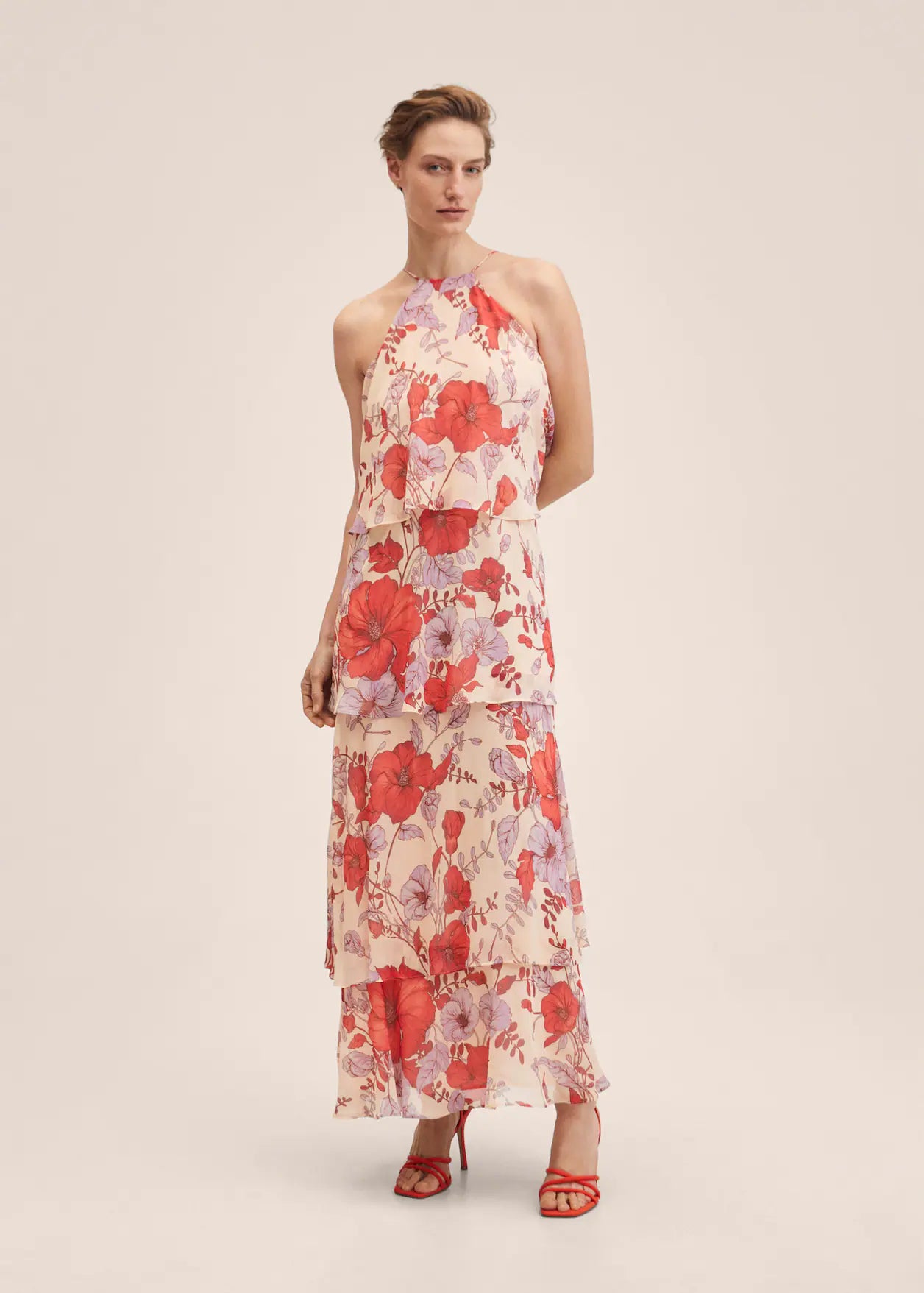 Estampado de flores en tonos rojos y lilas con diseño evasé de volantes, cuello halter y espalda abierta. Con tirantes finos con cierre de lazo, cuesta 69,99 euros. 