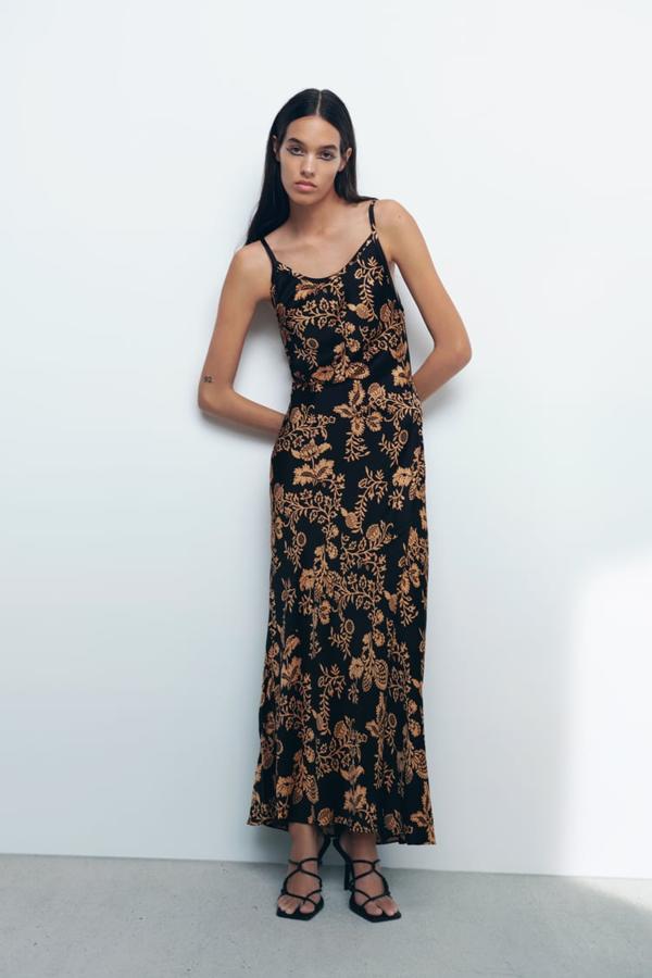 Diseño largo y escote fluido para este vestido negro de Zara con estampado de flores en color café que tiene tirantes finos y falda con ligero vuelo. Tiene un precio de 39,95 euros. 