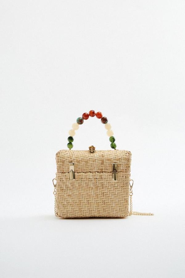 Confeccionado en ratán y con cuerpo trenzado, este bolso caja de Zara que viene con asa de mano de abalorios y asa de cadena en función bandolera extraíble tiene un precio de 39,95 euros.