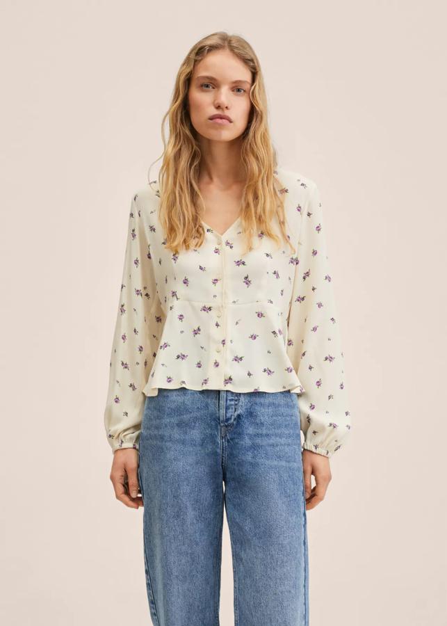 Estampado de flores lilas sobre fondo crudo para esta bonita blusa en tejido ligero con cuello redondo que está confeccionada en tejido fluido y es de diseño crop recto. Con mangas largas con puños elásticos y volante en la cintura, está rebajada y de 22,99 euros ha pasado a costar 15,99 euros. 