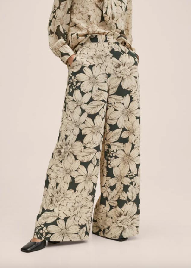 Diseño palazzo para este pantalón de Mango con estampado de flores en tonos grises sobre fondo en verde oscuro y elástico en la parte posterior de la cintura que tiene un precio de 39,99 euros. 
