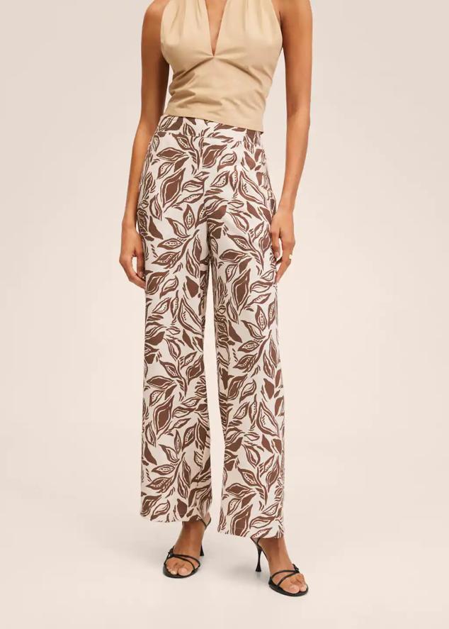 Diseño palazzo para estos pantalones blancos con estampado de hojas marrones de Mango que viene con fruncido elástico en la cintura y dos bolsillos laterales. Tienen un precio de 25,99 euros. 