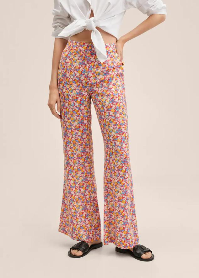 Fondo rojo y estampado de flores en blanco, azul y amarillo para estos pantalones de Mango de diseño wideleg, con tiro medio y fruncido elástico en la cintura. Tiene un precio de 39,99 euros. 