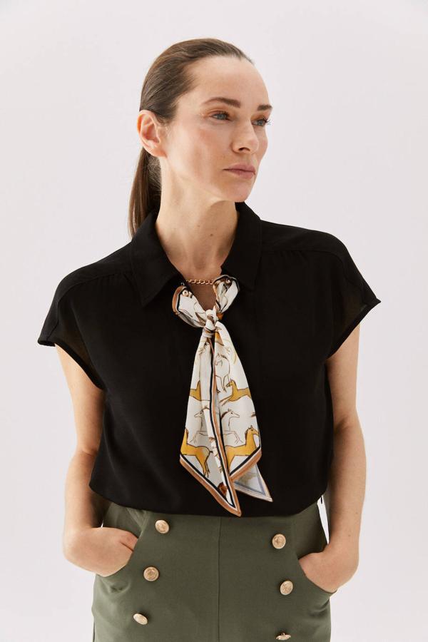 En Cortefiel encontramos esta camisa lisa de manga corta caída que se caracteriza por su diseño multicuello, ya que tiene cuello solapa, detalle de cadena dorada y pañuelo estampado extraíbles, disponible en negro y blanco y de las tallas XS a la XXL, con un precio de 49,99 euros.