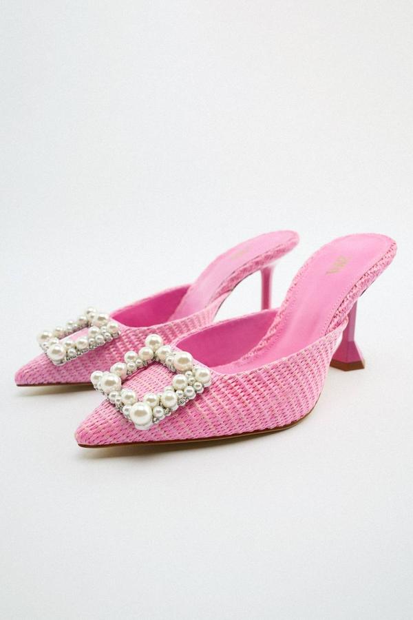 Zapatos destalonados de tacón confeccionados en tejido trenzado color rosa, acabados en punta y adornados en la pala con detalle de abalorio con perlas y cristales en forma de hebilla. Los encontrarás en Zara por 49,95 euros.